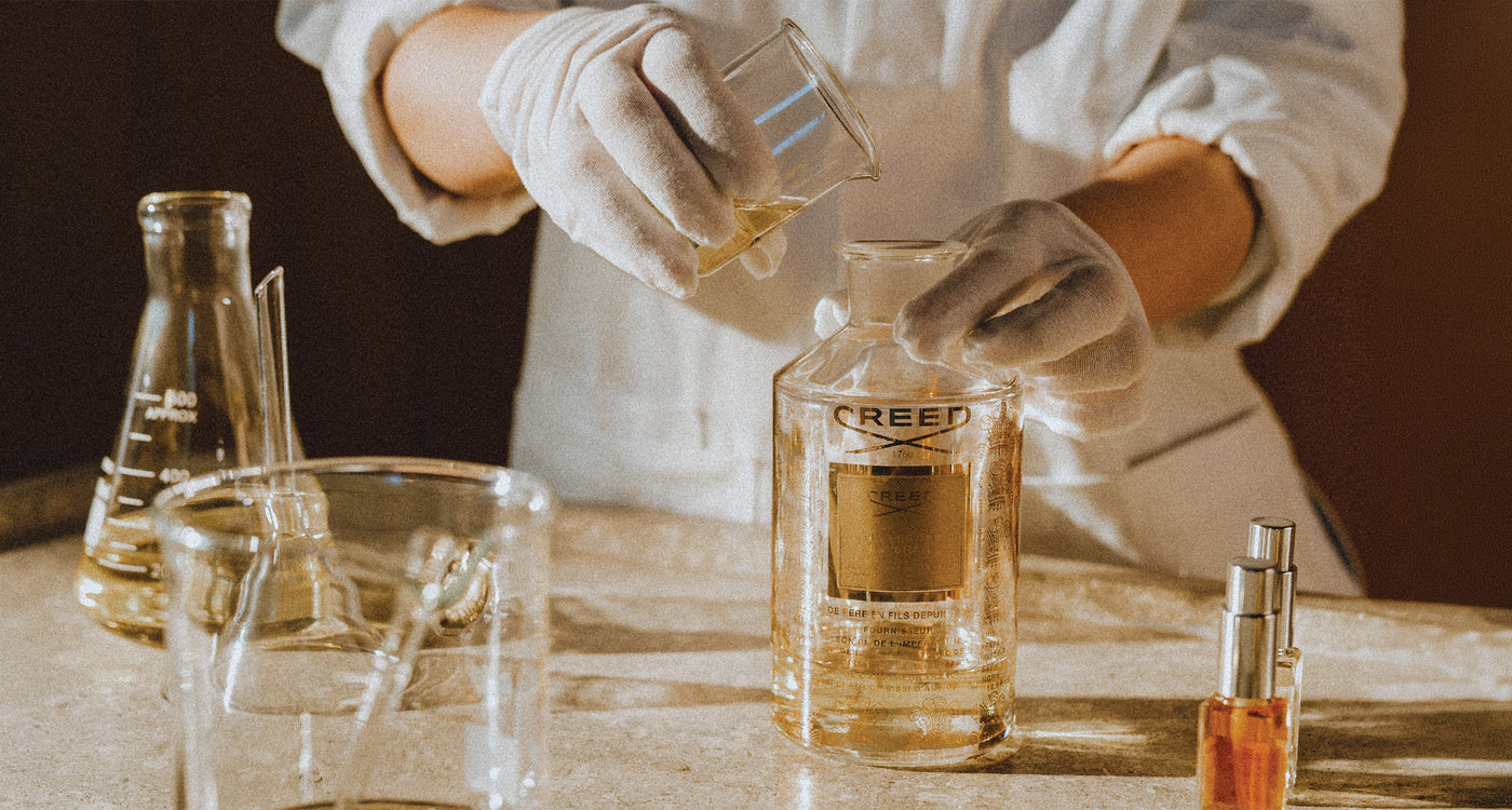 A Creed perfumer in white gloves pouring a fragrance sample at the atelier in Ury, France